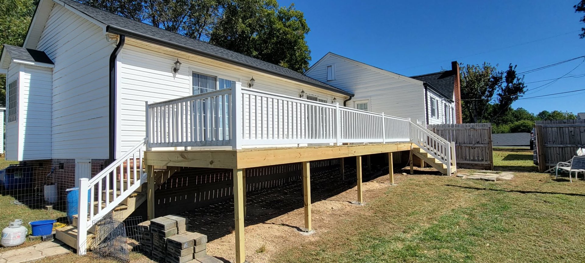 New elevated wood deck with white railings on white home