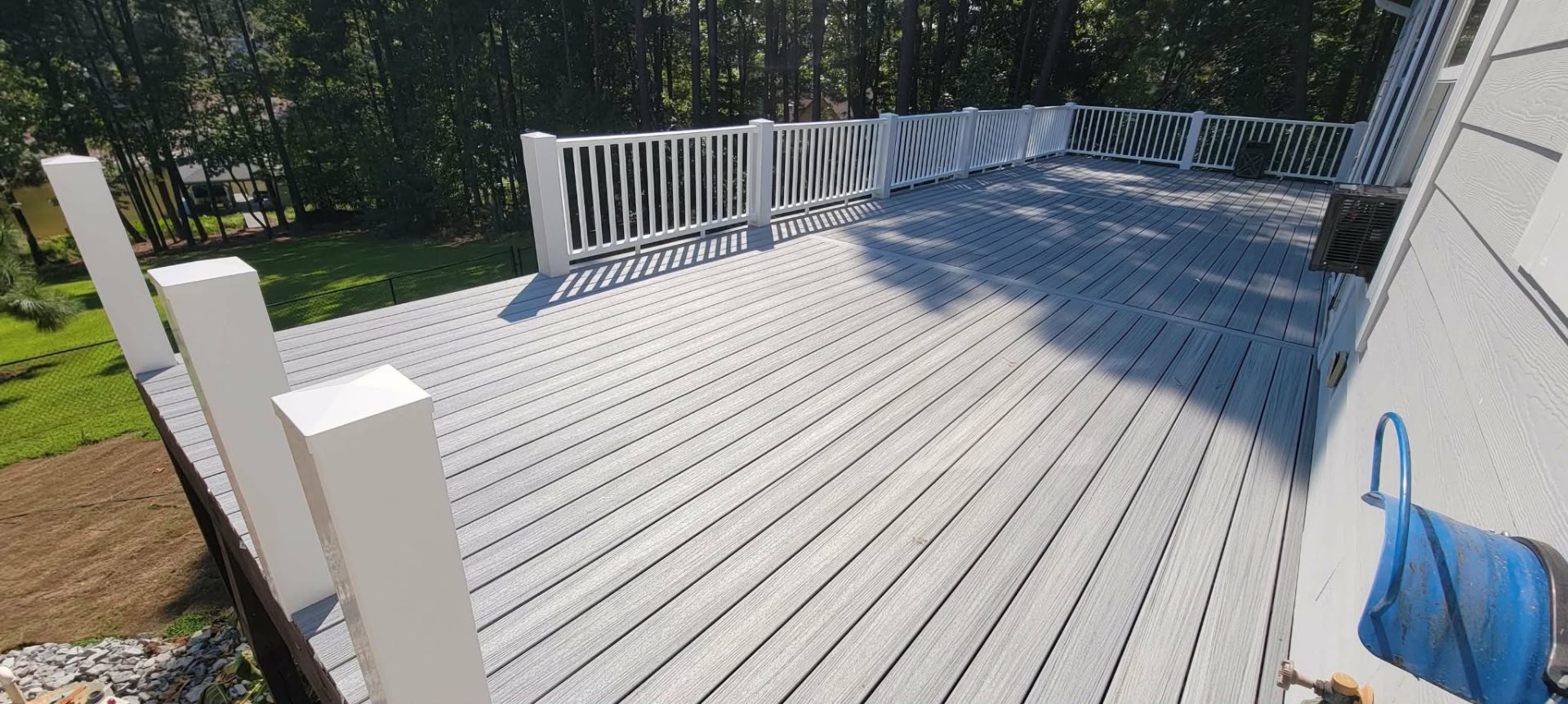 Large gray composite deck overlooking wooded backyard