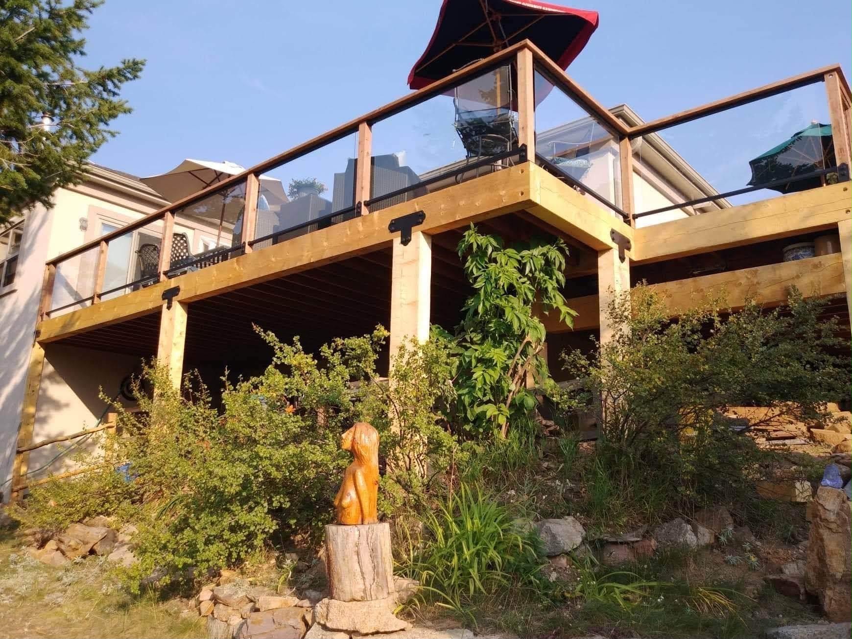 Elevated cedar deck with glass and steel railing on hillside home