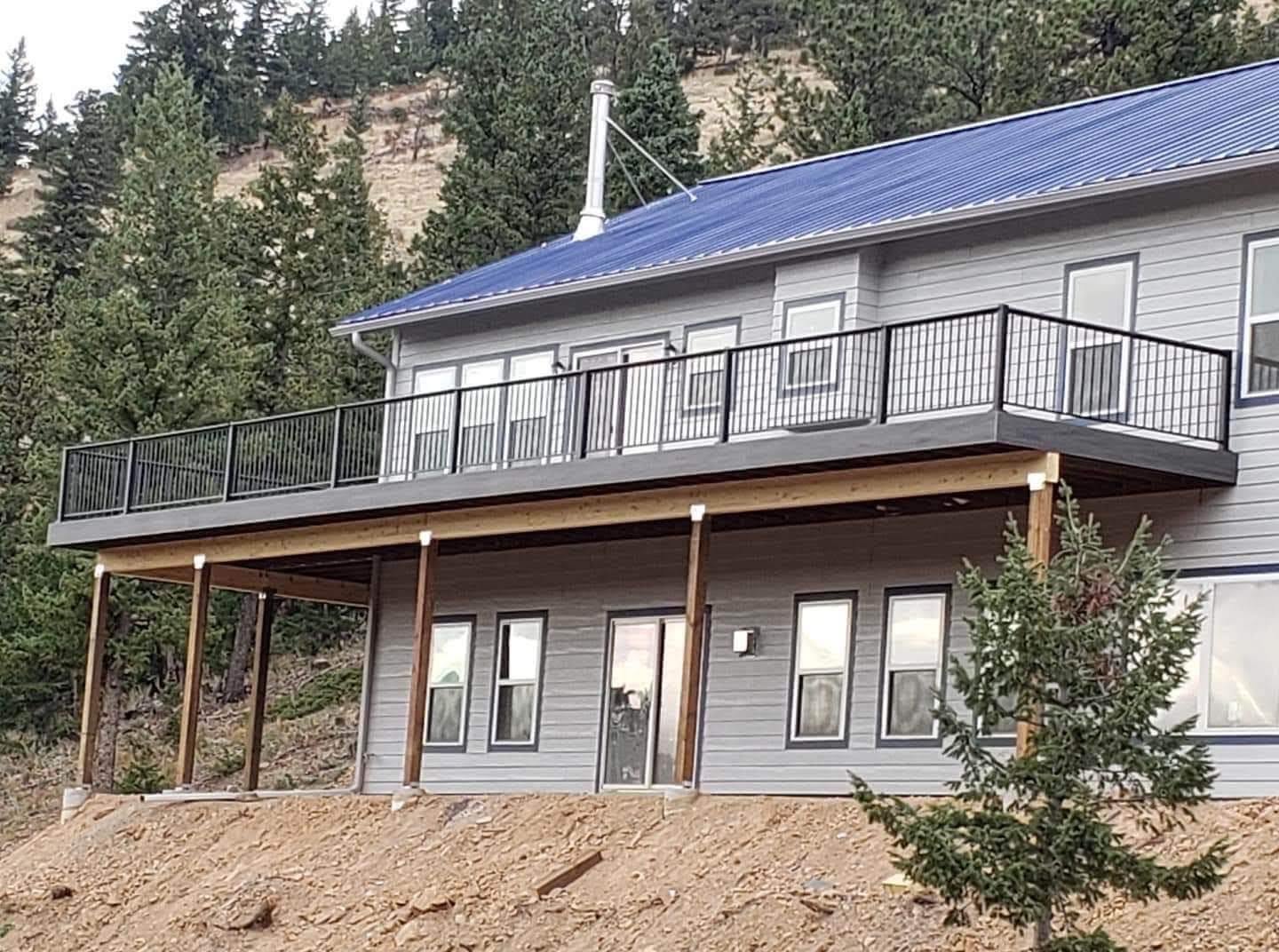 Second-story composite deck with black metal railing on mountainside home